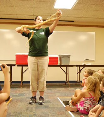 An Akron Zoo specialist holds up a snake to a crowd of children