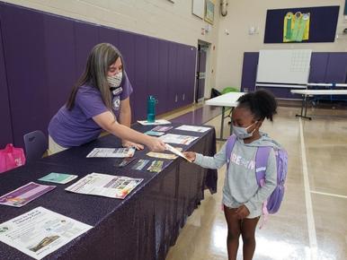 Children's Library Alison handing literature to child at elementary school