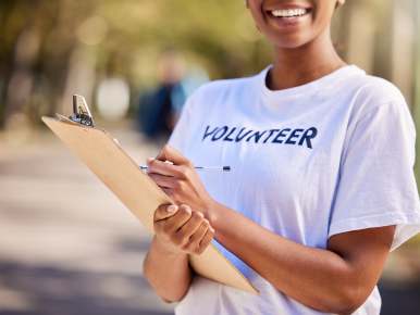 Girl in volunteer shirt writing on a clipboard