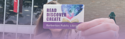 A person holds up a Barberton Public Library card that reads "Read, Discover, Create."