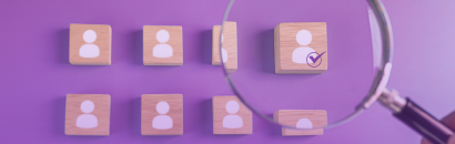 Magnifying glass over blocks with person icons on them.