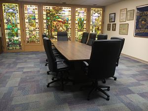 Board Room meeting table with chairs and O.C. Barber Mansion stained-class windows in the background.