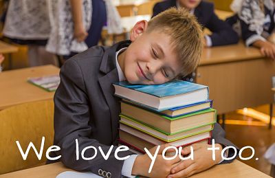 text reads 'we love you too' over an image of a young boy in a suit sitting at a desk, laying his head on a stack of books, smiling.